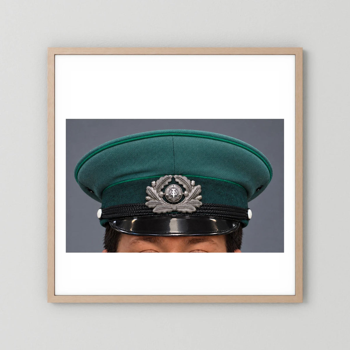 East German Volkpolizei (People's Police), Visor Cap, January 1989 — photograph displayed in a natural oak frame mockup