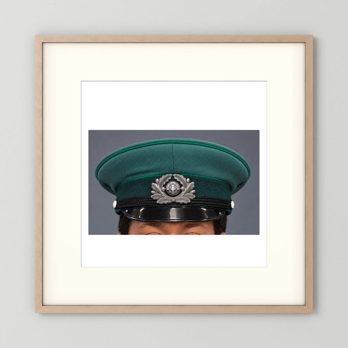 East German Volkpolizei (People's Police), Visor Cap, January 1989 — photograph displayed in a natural oak frame mockup