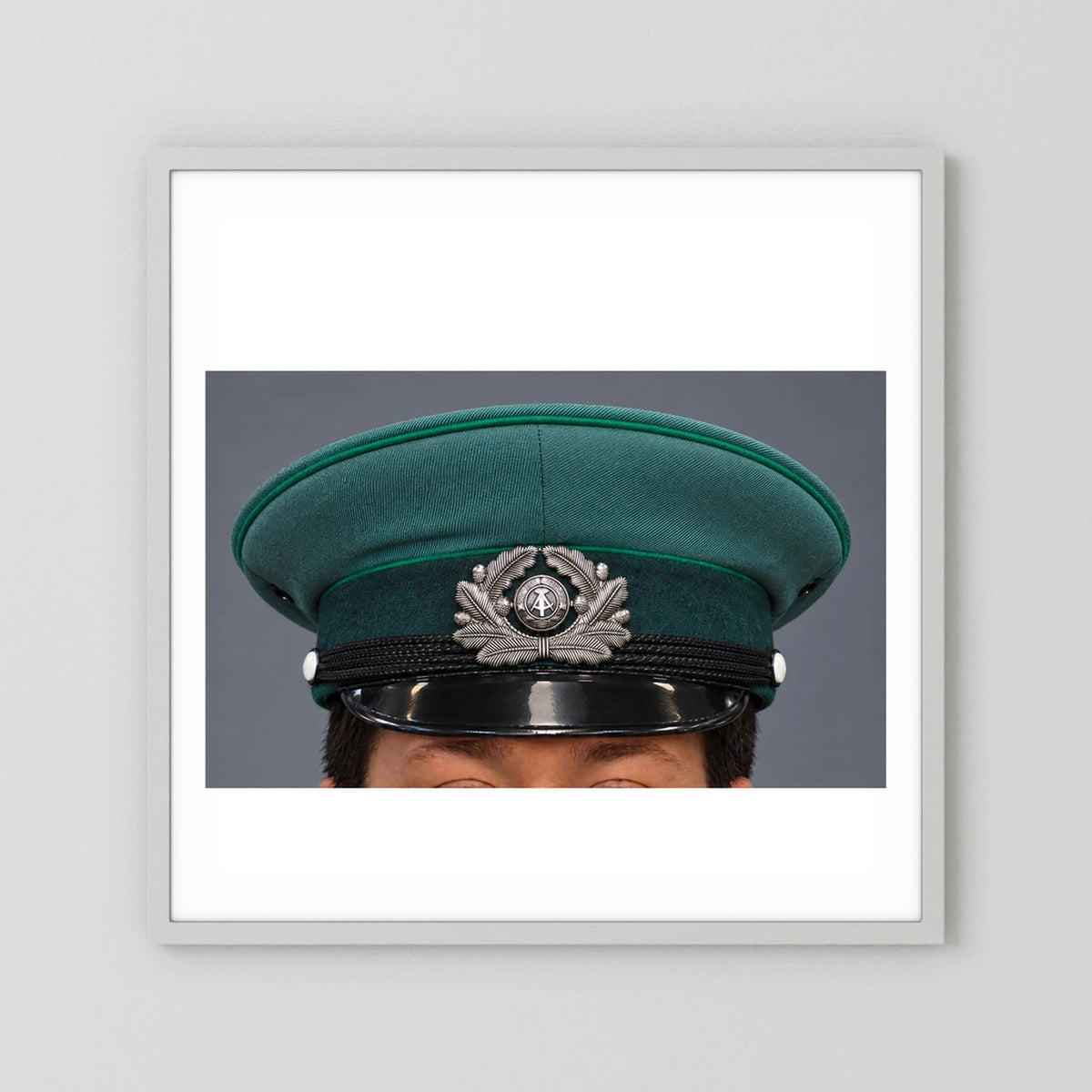 East German Volkpolizei (People's Police), Visor Cap, January 1989 — photograph displayed in a white wood frame mockup