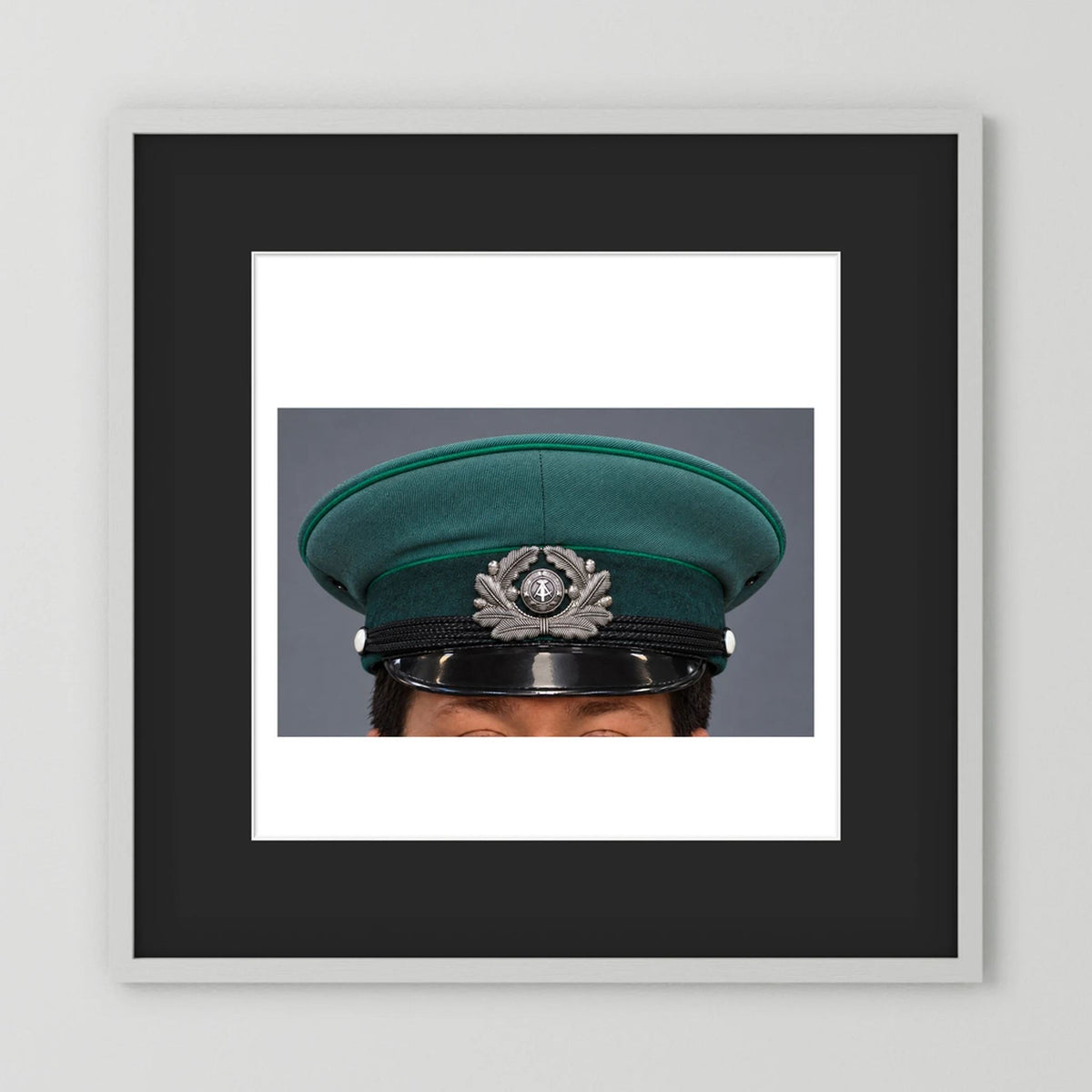 East German Volkpolizei (People's Police), Visor Cap, January 1989 — photograph displayed in a white wood frame mockup